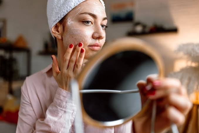 Woman applying aloe vera gel as an overnight remedy for open pores.